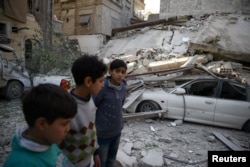 Children are seen near rubble after an airstrike in the besieged town of Douma, in eastern Ghouta, near Damascus, Syria, Feb 6, 2018.