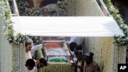 Husband Boney Kapoor, top, actors Anil Kapoor, third left and Arjun Kapoor, second left, stand beside as the body of Indian actress Sridevi covered with the Indian flag is carried in truck during her funeral in Mumbai, India, Wednesday, Feb. 28, 2018.