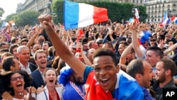 French soccer fans celebrate after France scored the first goal, as they watch the World Cup soccer match between France and Nigeria being shown live on a giant screen, in front of Paris City Hall, June 30, 2014.