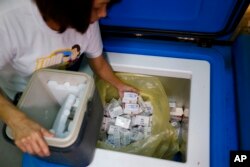 FILE - A Manila Health officer puts back into a refrigerated storage, boxes of the anti-dengue vaccine Dengvaxia after being recalled from local government health centers.