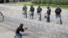 FILE - A Cambodian woman takes a photo of riot police standing behind bard wire at Freedom Park in Phnom Penh, May 1, 2014. U.S.-based Cambodian community activists are campaigning for a congressional resolution calling for human rights, democracy and the rule of law in Cambodia.