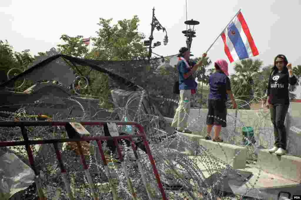 A woman poses on a downed barricade at the entrance to the government complex in Bangkok, Dec. 3, 2013. (Steve Herman/VOA)