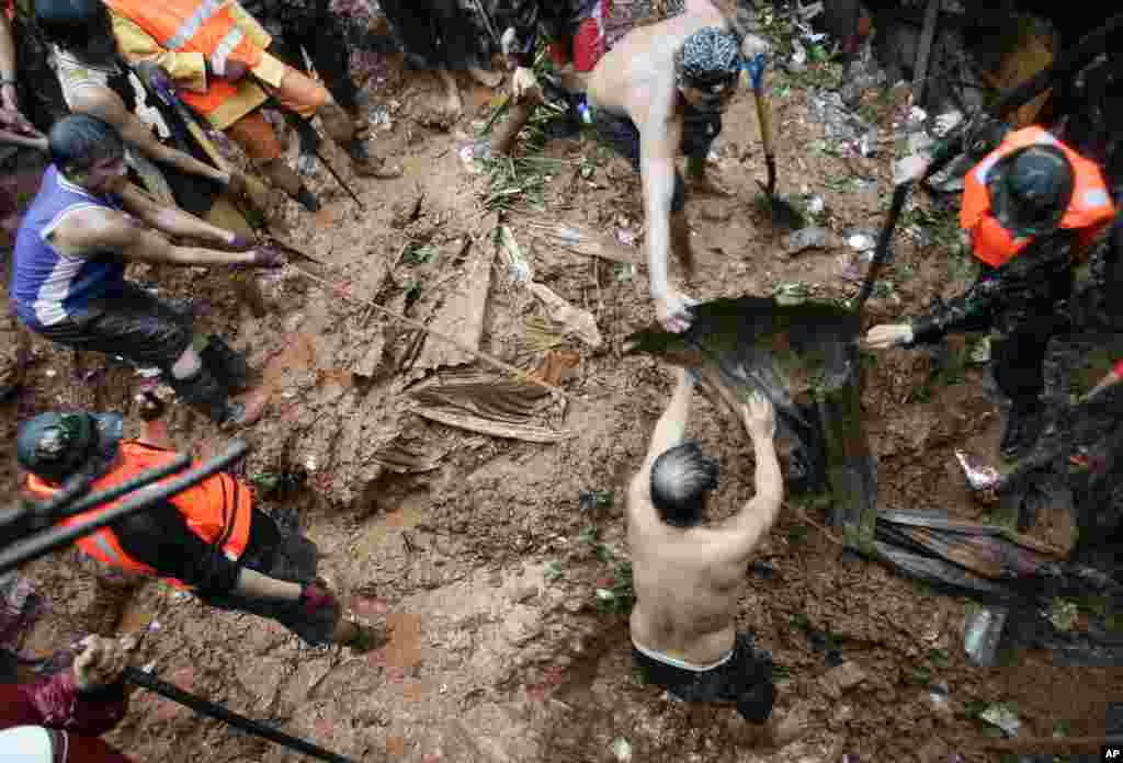 Relawan Filipina melakukan penggalian untuk mencari korban selamat di lokasi di mana empat rumah tertimbun tanah longsor di Quezon City (7/8).