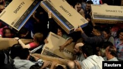 Shoppers reach out for television sets as they compete to purchase retail items on Black Friday at a store in Sao Paulo, Brazil, Nov. 23, 2017. 