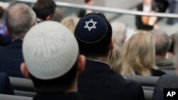 FILE - Two men wearing skullcaps as they listen to a speech by Israeli historian Saul Friedlaender, during a Holocaust remembrance event at the Reichstag building in Berlin, Germany, Jan. 31, 2019.
