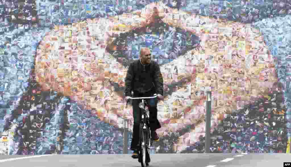 Seorang pengendara sepeda naik melewati billboard kampanye pemilu raksasa di kota Berlin, yang menampilkan tangan Kanselir Jerman Angela Merkel menjelang pemilu 22 September.