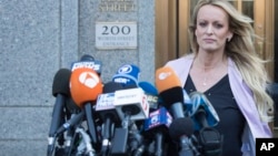 Adult film actress Stormy Daniels approaches the microphones set up outside federal court to address reporters, April 16, 2018, in New York. 