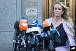 Adult film actress Stormy Daniels approaches the microphones set up outside federal court to address reporters, April 16, 2018, in New York.