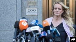 FILE - Adult film actress Stormy Daniels approaches the microphones set up outside federal court to address reporters, April 16, 2018, in New York. 