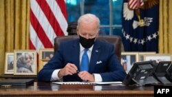 FILE - US President Joe Biden signs executive orders related to immigration in the Oval Office of the White House in Washington, DC, February 2, 2021. (Photo by SAUL LOEB / AFP)