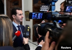 FILE - Syria's President Bashar al-Assad speaks to journalists in Damascus, Syria, Jan. 9, 2017. Iraqi firebrand cleric Moqtada al-Sadr is calling on Assad to resign to help Syria avoid the menace of war and dominance of terrorists.