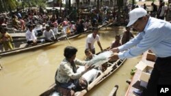 A villager receives flood donations for her family while others wait for their turn on boats at Prek Sussey, Kandal province, some 50 kilometers (31 miles) east of Phnom Penh, Cambodia, Tuesday, Oct. 18, 2011. 