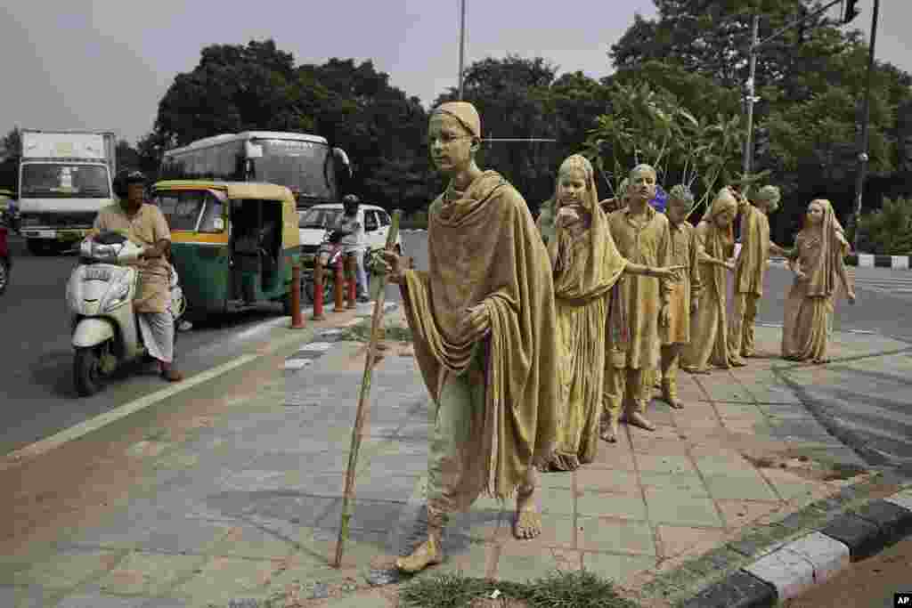 School children dressed up as statues, depicting Indian freedom leader Mahatma Gandhi&#39;s Dandi March, stand at a traffic intersection on the eve of Gandhi&#39;s 150th birth anniversary in New Delhi.