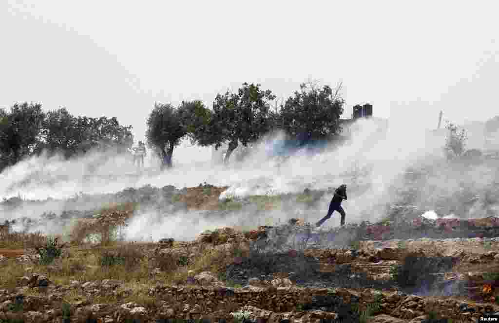 A Palestinian demonstrator runs from tear gas fired by Israeli troops during a protest in solidarity with prisoners on hunger strike, outside Ofer prison near the West Bank city of Ramallah.