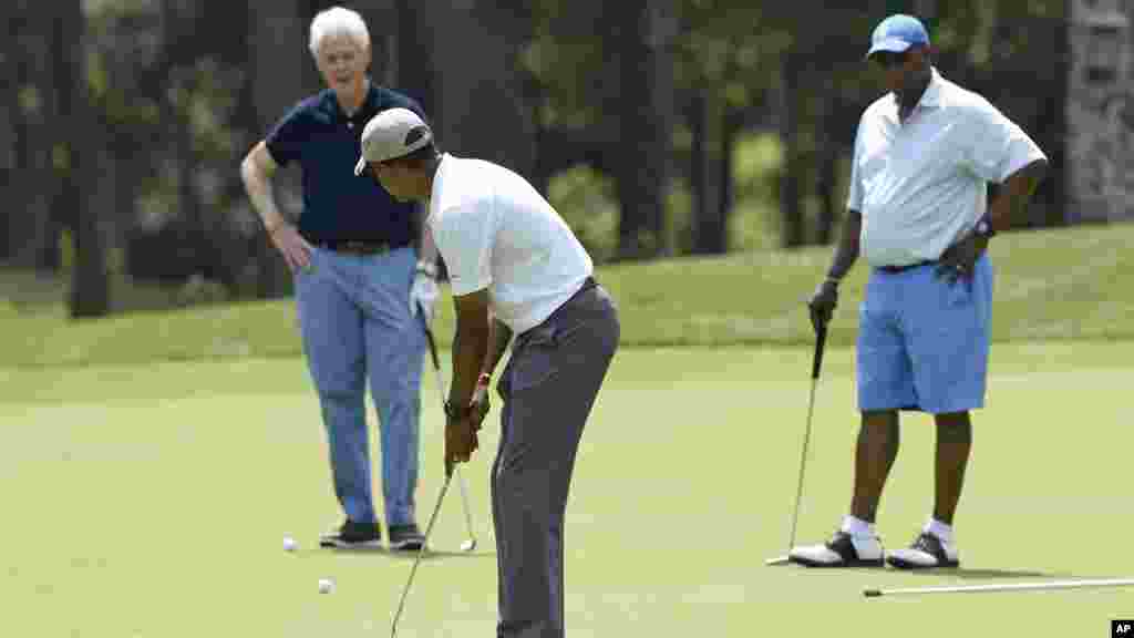Barack Obama prend position pour frapper la balle sous le regard de Bill Clinton et Ron Kirk (l&#39;ancien représentant du commerce américain), 15 août 2015