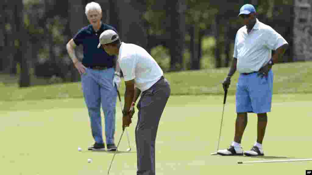 Barack Obama prend position pour frapper la balle sous le regard de Bill Clinton et Ron Kirk (l'ancien représentant du commerce américain), 15 août 2015