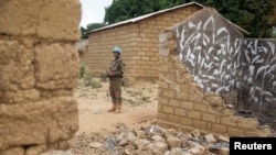 FILE - A United Nations peacekeeper stands among houses destroyed by violence in the abandoned village of Yade, Central African Republic, April 27, 2017.