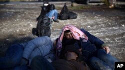 Syrian refugees wait to be picked up by the police on the outskirts of the northern Greek city of Thessaloniki, Nov. 30, 2016. 