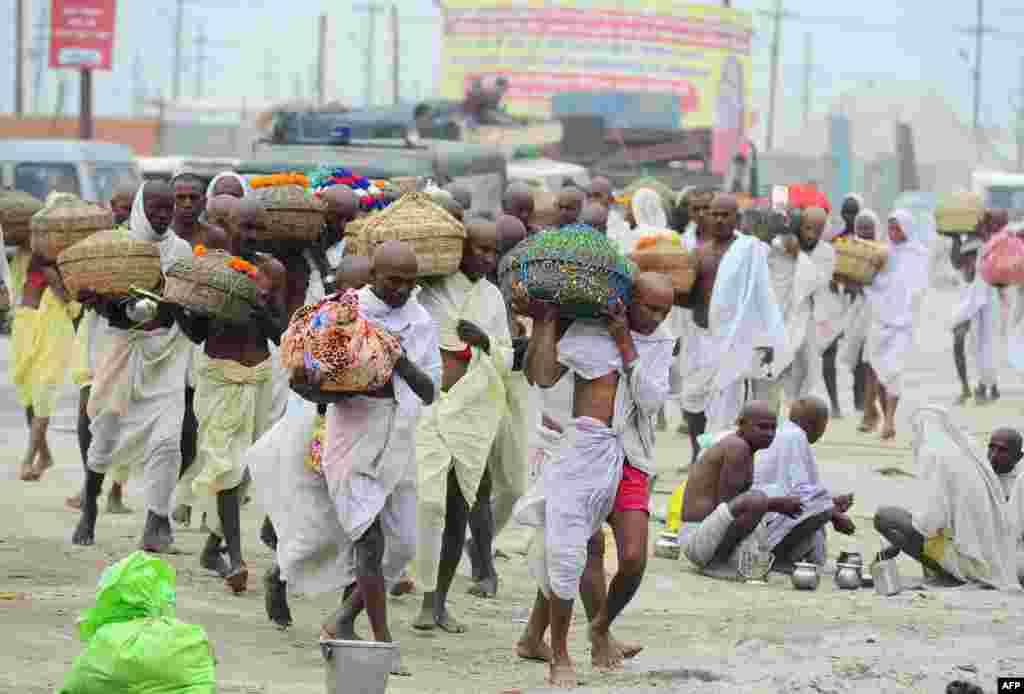 Para pendeta Hindu Nepal membawa air suci dari sungai Gangga setelah mereka pulang dari ritual mandi suci di Sangam, India.
