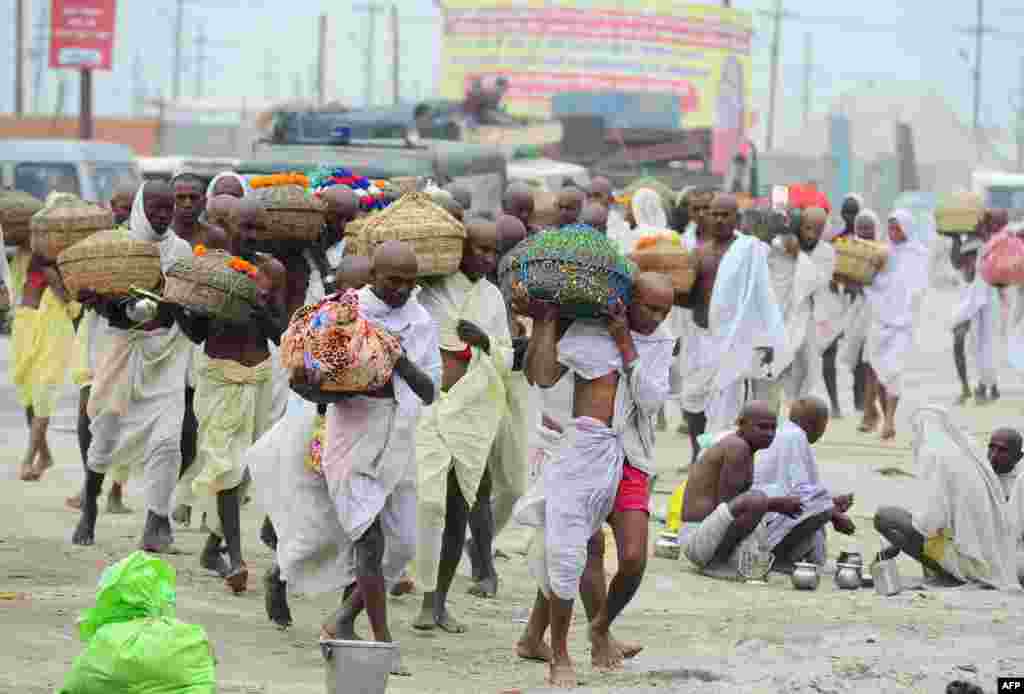 Priests from Nepal carry holy water from the River Ganges as they return after taking a Holy dip at the Sangam, the confluence of the rivers Ganges, Yamuna and mythical Saraswati in Allahabad, India.