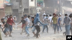 FILE - Cambodia garment workers throw stones at riot police during a strike near a factory on the Stung Meanchey complex on the outskirts of Phnom Penh, Cambodia, Friday, Jan. 3, 2014.