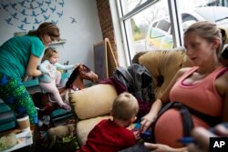Moira Brennen, 33, left, puts her daughter Audrey, 2, on a rocking horse while meeting at a coffee shop with fellow stay-at-home mother Jessica Greene, 37, and her son, Woods, 2, in East Atlanta, Georgia, in DeKalb County, Jan. 5, 2017.
