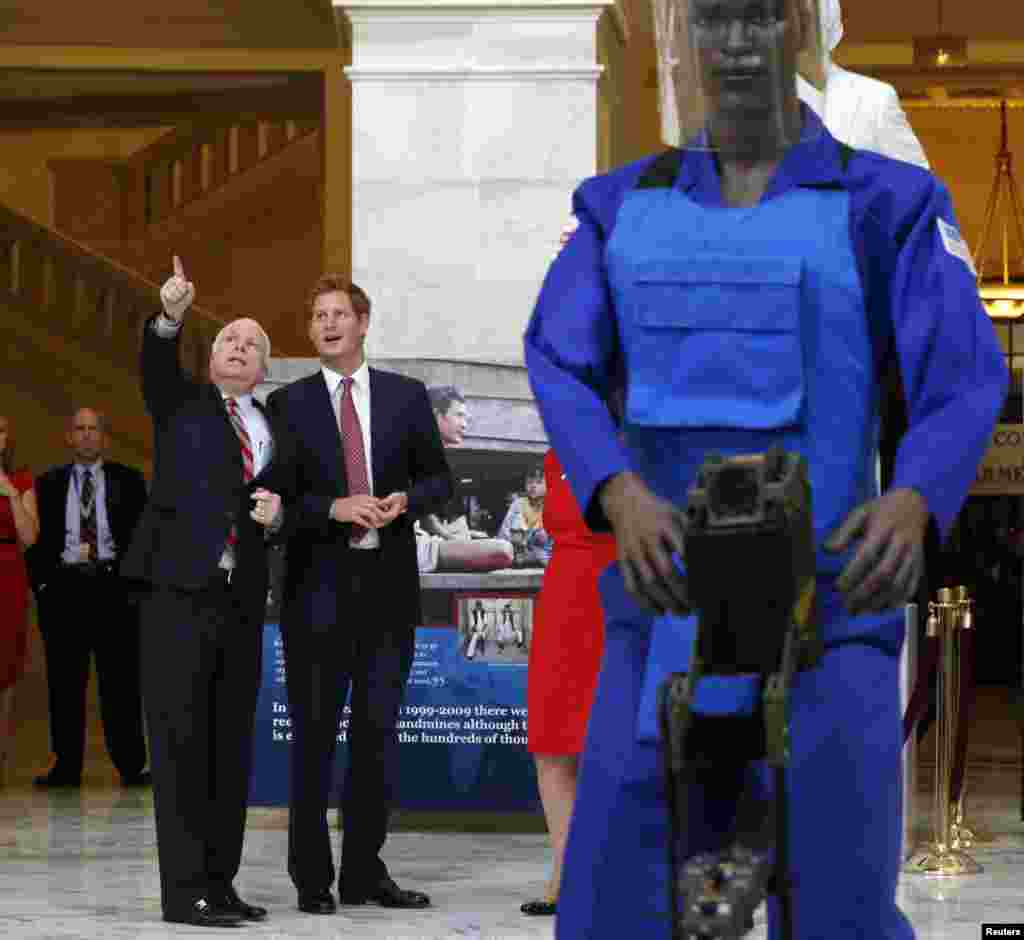 Britain's Prince Harry is pictured alongside a mannequin dressed as a landmine detector during a tour of a Halo Trust exhibit in the Russell Building of the U.S. Capitol in Washington, May 9, 2013. Pictured with Prince Harry is U.S. Senator John McCain (R