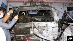 کابل میں صحافی ڈرون حملے سے ایک گھر میں کھڑی تباہ ہونے والی گاڑی کی تصویریں لے رہے ہیں۔ 29 اگست 2021