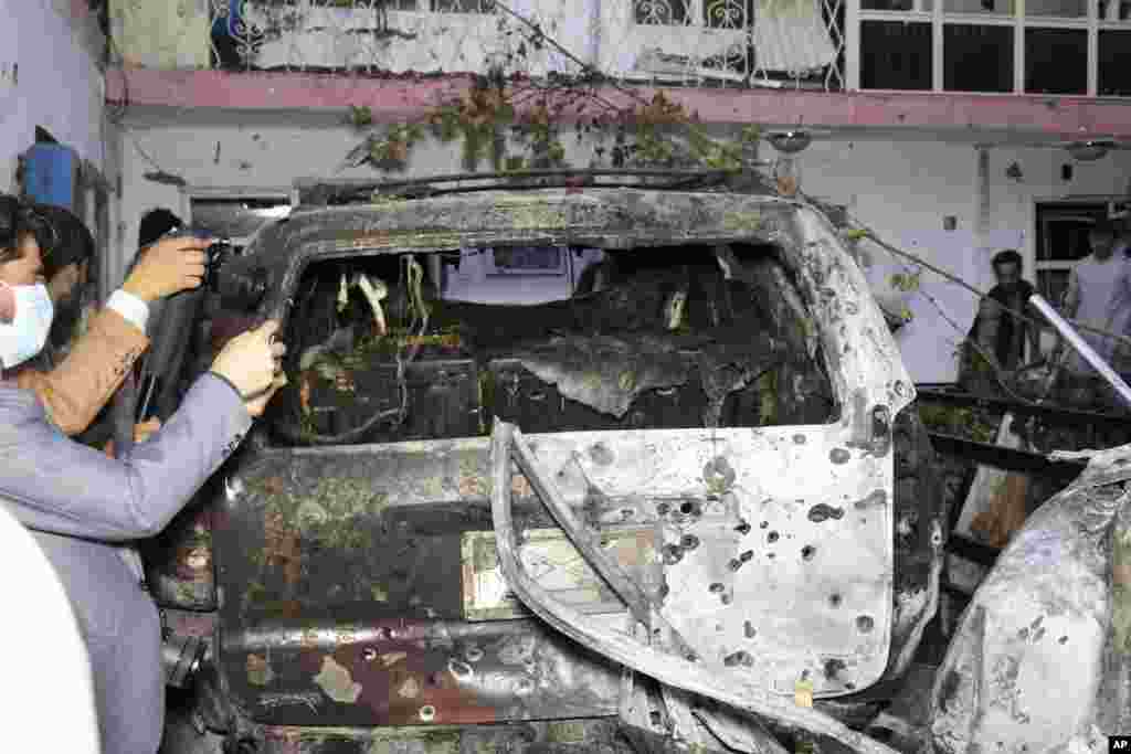 Afghan journalists take a photos of destroyed vehicle inside a house after U.S. drone strike in Kabul. A U.S. drone strike destroyed a vehicle carrying &quot;multiple suicide bombers&quot; from Afghanistan&#39;s Islamic State affiliate before they could attack the ongoing military evacuation at Kabul&#39;s international airport, American officials said.
