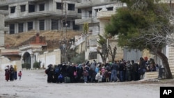 FILE - Syrians wait for an aid convoy in the besieged town of Madaya in the countryside of Damascus, Syria, Jan. 14, 2016, as part of a U.N.-sponsored aid operation in this war-torn country. 