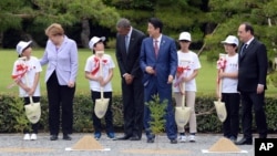 German Chancellor Angela Merkel, second left, U.S. President Barack Obama, fourth left, chat with children who brought shovels for them during a tree planting ceremony at Ise Jingu shrine in Ise, Mie Prefecture, Japan, Thursday, May 26, 2016. (Ma Ping/Pool Photo via AP)