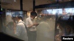 People check their phones in a smoking room at Shinagawa Station amid the coronavirus disease (COVID-19) outbreak, in Tokyo, Japan, Aug. 2, 2021.