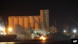 Smoke billows from a ship on fire at the seaport in Tripoli, May 20, 2011