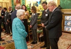 Ratu Elizabeth II Inggris berbicara dengan Perdana Menteri Inggris Boris Johnson, kanan, pada resepsi Global Investment Summit di Windsor Castle, 19 Oktober 2021. (Foto: Arthur Edwards via AP)