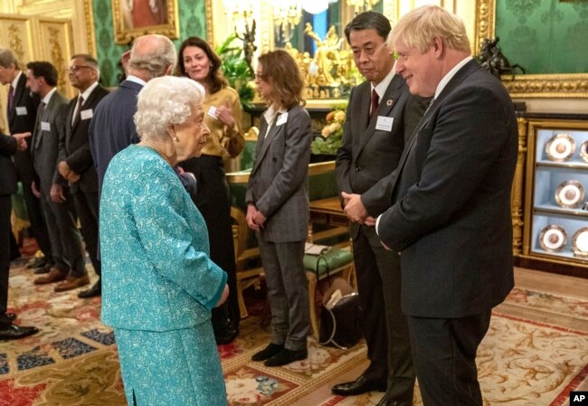 Ratu Elizabeth II Inggris berbicara dengan Perdana Menteri Inggris Boris Johnson, kanan, pada resepsi Global Investment Summit di Windsor Castle, 19 Oktober 2021. (Foto: Arthur Edwards via AP)
