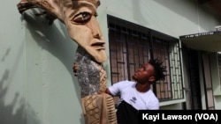 Atisso Goha, un artiste togolais qui sculpte des œuvres géantes en bois, à Lomé, Togo, le 19 avril 2019. (VOA/Kayi Lawson)