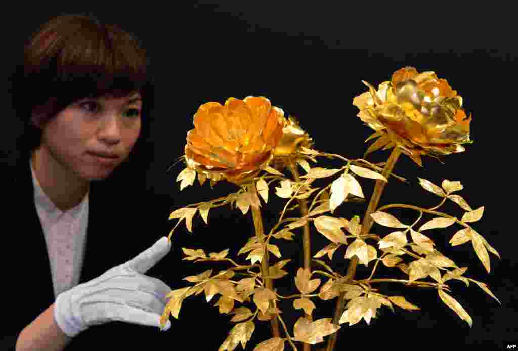 A department store employee displays flowers made of pure gold, 4.2kg in weight and priced at 157 million yen (1.7 million USD) at the &quot;Gold Expo&quot; exhibition at Tokyo&#39;s Matsuzakaya department store, Japan.