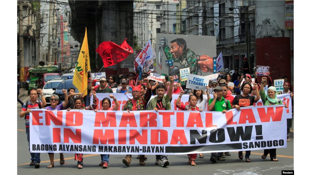Activists display a banner and a mural of President Rodrigo Duterte to denounced the declaration of martial law in Mindanao island, one year after Islamic militants occupied parts of the southern Philippine city of Marawi during a protest in Manilla.