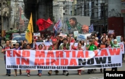 Activists display a banner and a mural of President Rodrigo Duterte to denounced the declaration of martial law in Mindanao island, one year after Islamic militants occupied parts of the southern Philippine city of Marawi during a protest in Manilla.