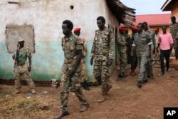 FILE - South Sudanese soldiers accused of raping and killing foreign aid workers on the Terrain hotel compound are assisted to a prison van after attending their trial in Juba, South Sudan, May 30, 2017.