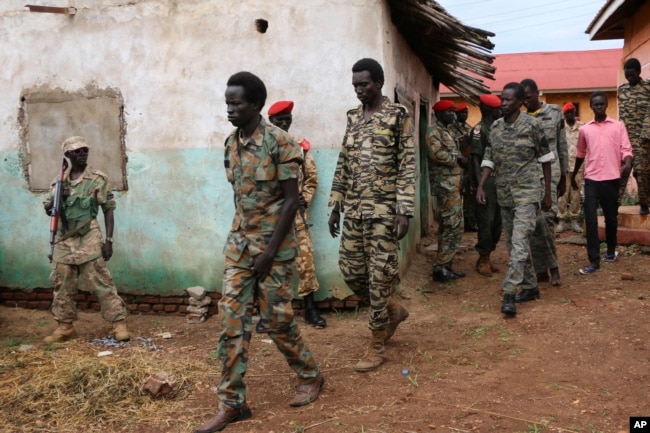 FILE - South Sudanese soldiers accused of raping and killing foreign aid workers on the Terrain hotel compound are assisted to a prison van after attending their trial in Juba, South Sudan, May 30, 2017.