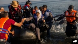 Migrants from Syria and Afghanistan arrive on an overcrowded dinghy from the Turkish coasts to the Greek island of Lesbos, Monday, July 27, 2015. 