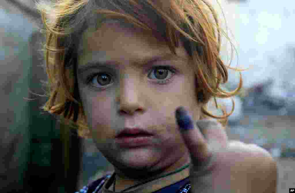 Seorang anak perempuan menunjukkan jari bertinta tanda sudah mendapatkan vaksinasi polio di Lahore (19/12/2012). (AP/K.M. Chaudary)