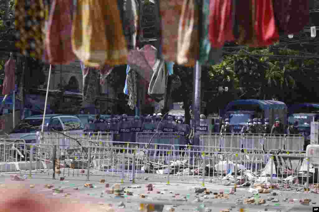 Myanmar riot police stand in front of road barricade, as protesters hang women&#39;s sarongs overhead in Yangon, Myanmar. There is a traditional belief that walking underneath women&#39;s sarongs (htamein) will bring bad luck especially to men.