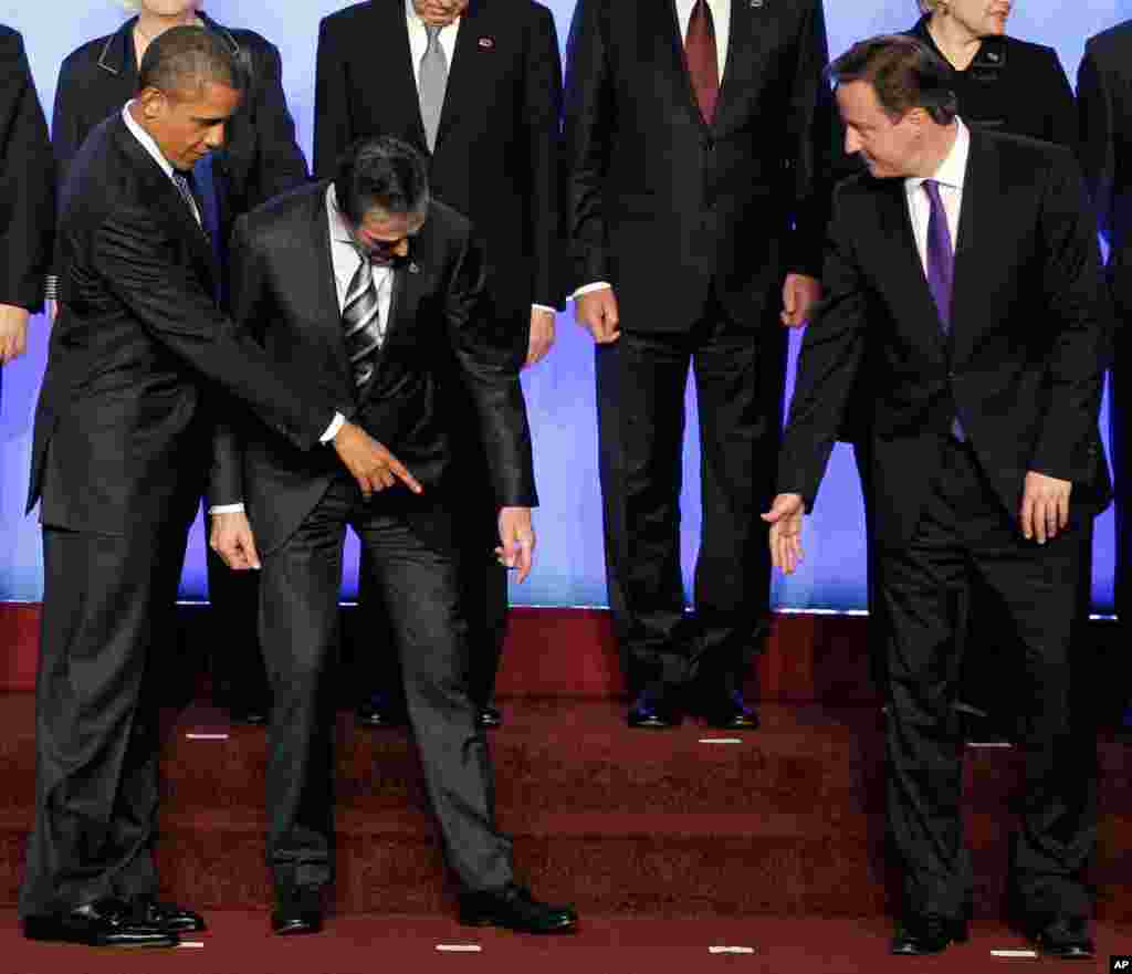 President Barack Obama and British Prime Minister David Cameron help Secretary General Anders Fogh Rasmussen find his toe marker. (AP)