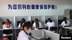 中國遼寧省沈陽市精神健康熱線電話服務站裡戴著口罩的輔導人員為打來求助電話的人提供幫助。（2020年2月12日）