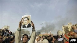 Trong cuộc biểu tình tại thủ đô Cairo ngày 29 tháng 1 năm 2011, một người biểu tình Ai Cập giương hình Tổng thống Hosni Mubarak với những đường gạch trên hình và hàng chữ 'Mubarak, hãy ra đi' ở bên trên.