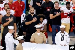 Kaepernick, at center, kneels during the national anthem before the NFL preseason football game against the San Diego Chargers, Sept. 1, 2016.