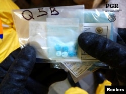 A chemical specialist in a protective suit shows pills seized at a clandestine drug processing laboratory of fentanyl in Mexico City. Similar pills were seized at the U.S. border Thursday by border protection officers.