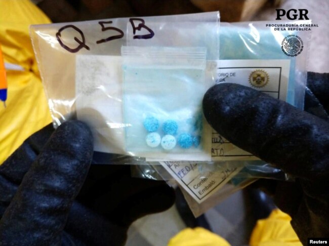 A chemical specialist in a protective suit shows pills seized at a clandestine drug processing laboratory of fentanyl in Mexico City. Similar pills were seized at the U.S. border Thursday by border protection officers.